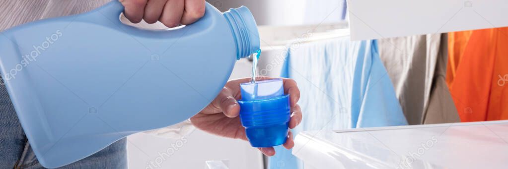 Close-up Of A Person's Hand Pouring Detergent In Lid