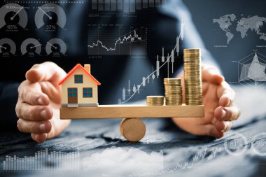 Küçük ev modeli ve yığılmış altın sikke üzerinde ahşap tahterevalli Dengeleme