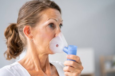 astım krizi önlemek için astım spreyi kullanarak kadınla