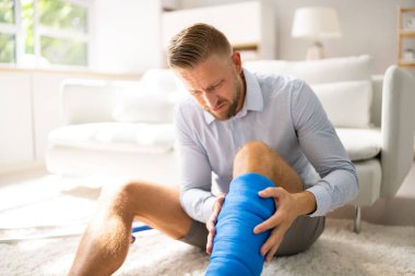 Kırık bacaklı, alçılı ve koltuk değnekli adam.