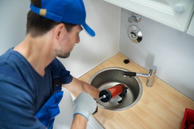 Plumber Cleaning Drain And Sink Using Pump