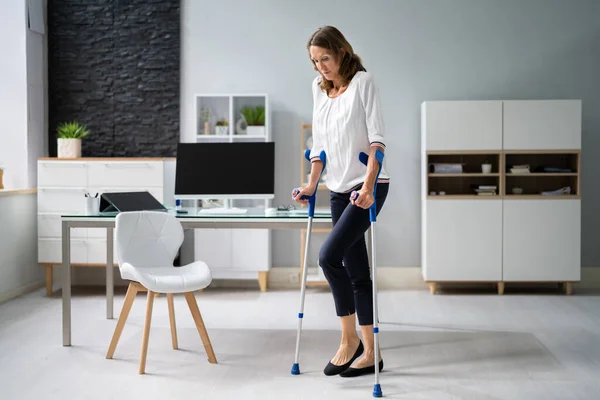 Injured Businesswoman Walking Hardwood Floor Crutches Workplace — Stok fotoğraf