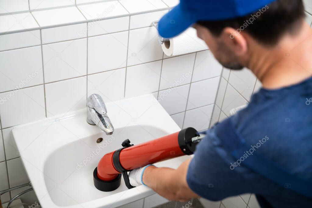 Plumber Cleaning Drain And Bathroom Sink Using Pump