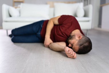 Unconscious Young Man Lying On Floor In Living Room clipart