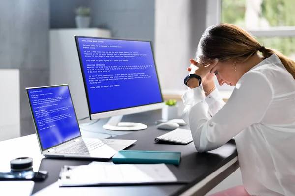 Worried Woman At Computer With System Failure Screen At The Workplace