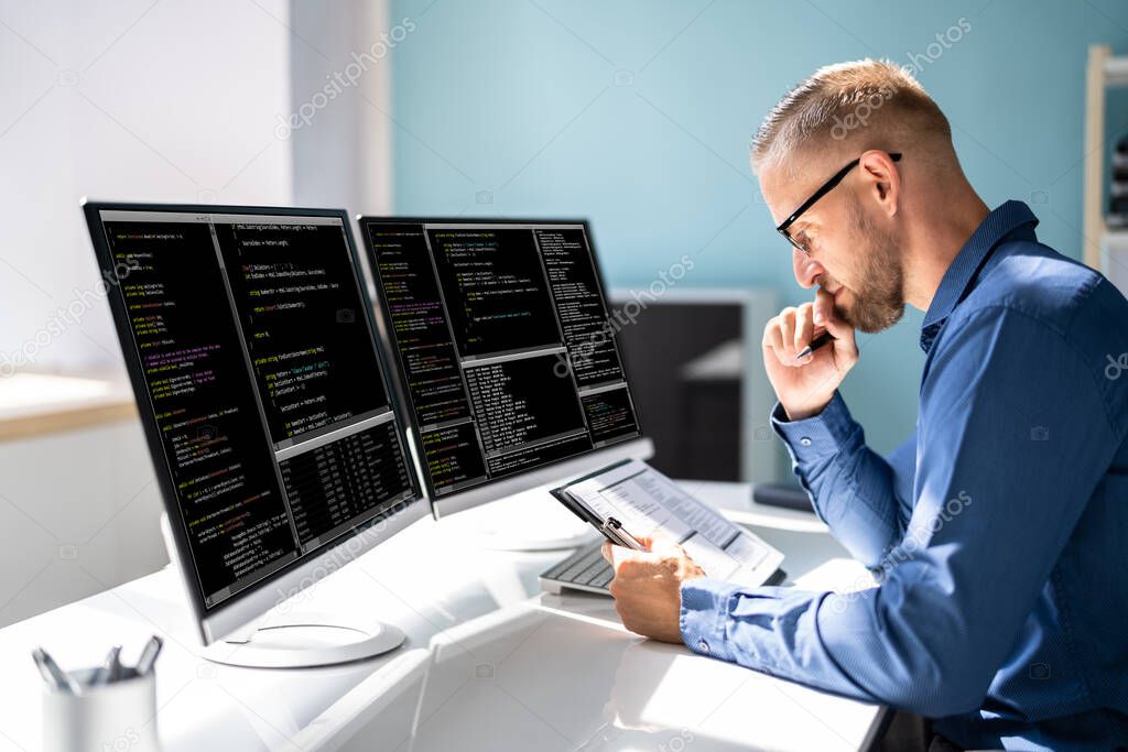 Computer Programmer Writing Program Code On Computer In Office