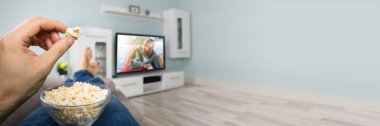 Kanepede patlamış mısır yemek, televizyon izlemek. Oturma odası