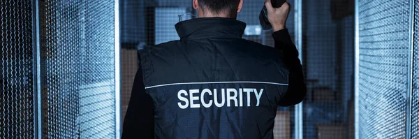 Security Guard With Flashlight At Night In Warehouse