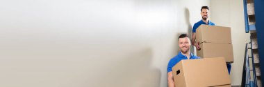 Nakliyeciler ekibi merdivenlerden aşağı kutu taşıyor. Mover Teslimat Servisi