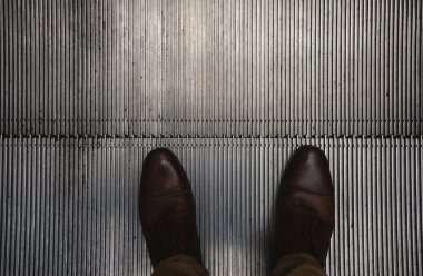 Erkek ayağına ve ayakkabı detaylarına odaklı yürüyen merdivenlerin ayrıntıları.