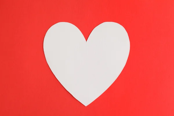 Papier kształt serca przez czerwone tło — Zdjęcie stockowe
