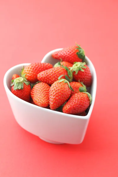 Tazón de fresa en forma de corazón sobre fondo rojo —  Fotos de Stock