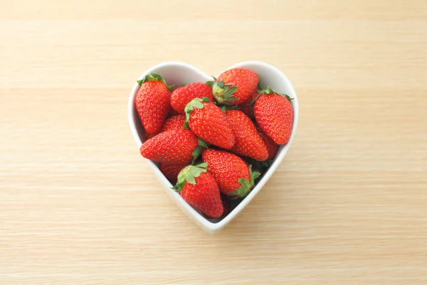 Strawberry in heart shape bowl on wooden background — Stock Photo, Image