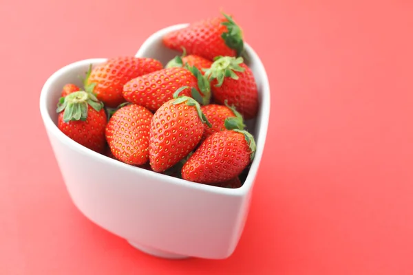 Strawberry in heart shape bowl on red background — Stock Photo, Image