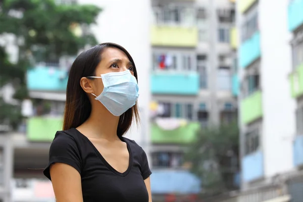 Orvosi maszkot viselő nő a zsúfolt városban. — Stock Fotó