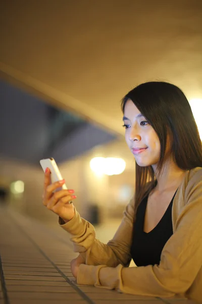 Mujer usando el teléfono en la ciudad por la noche — Foto de Stock