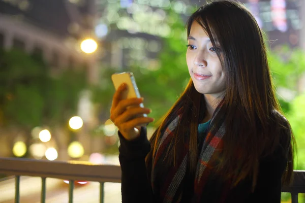 Mujer utilizar el teléfono móvil en la ciudad por la noche — Foto de Stock