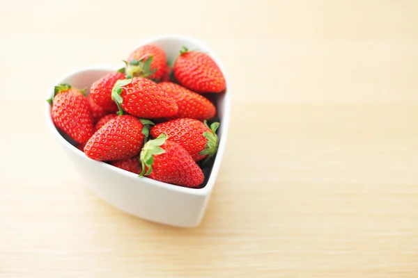 Strawberry in heart shape bowl on wooden background — Stock Photo, Image