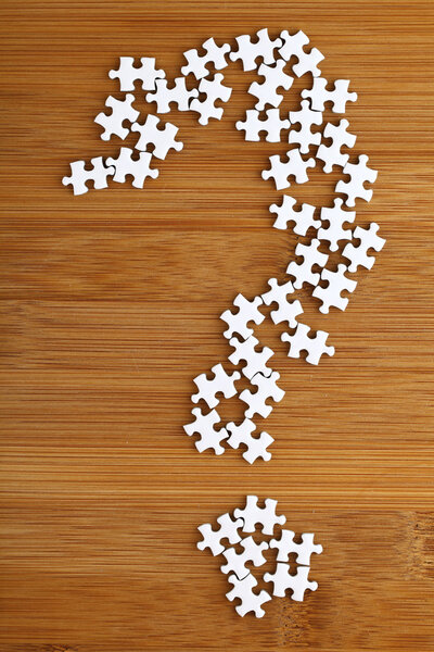 Question mark made by puzzle on wood background