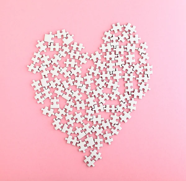 Quebra-cabeça feito forma de coração no fundo rosa — Fotografia de Stock