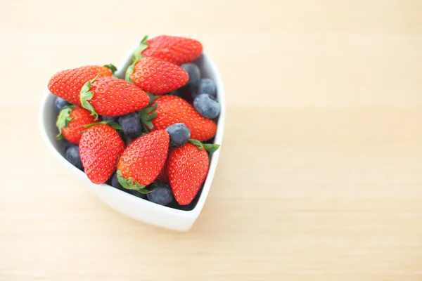 Strawberry in heart shape bowl on wooden background — Stock Photo, Image