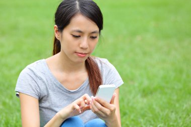 Asyalı kadını çimde Smartphone kullanarak