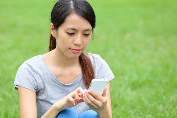 Asiatin benutzt Smartphone auf Gras — Stockfoto