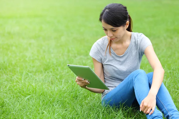 Kvinna sitter på gräset med tablet PC — Stockfoto