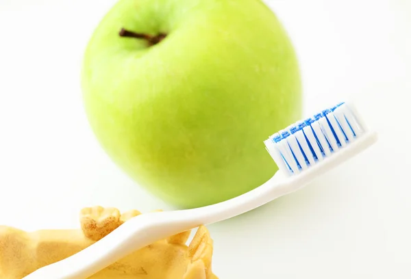 Концепция стоматологической помощи, зеленое яблоко и зубная щетка — стоковое фото