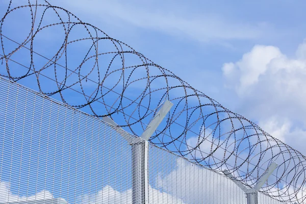 Maschendrahtzaun mit Stacheldraht unter blauem Himmel — Stockfoto