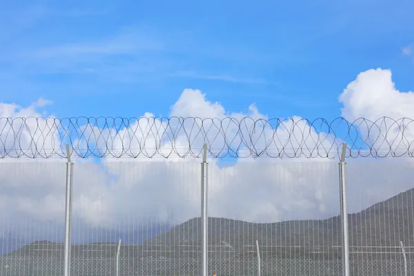 Řetězový plot s ostnatým drátem pod modrou oblohou — Stock fotografie
