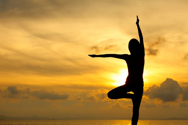 Silueta de una mujer yoga en la puesta del sol del mar —  Fotos de Stock