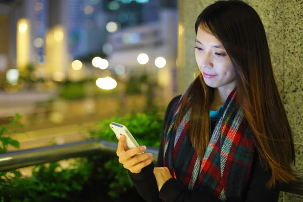 Женщина, использующая смартфон в городе ночью — стоковое фото