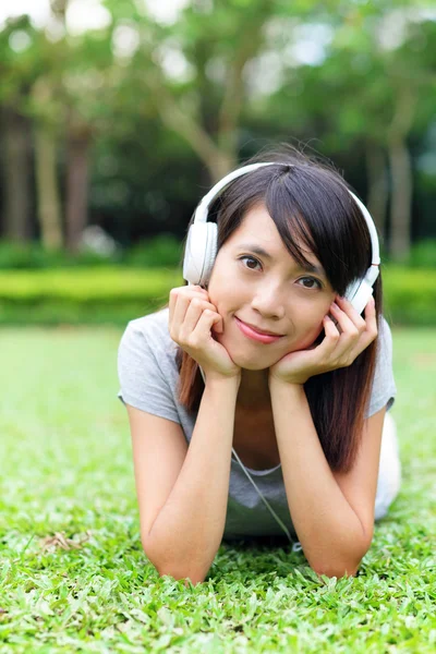 Asian woman listen to song lying on grass — Stock Photo, Image