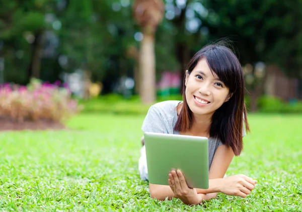 Frau liegt mit Tablet-Computer im Gras — Stockfoto