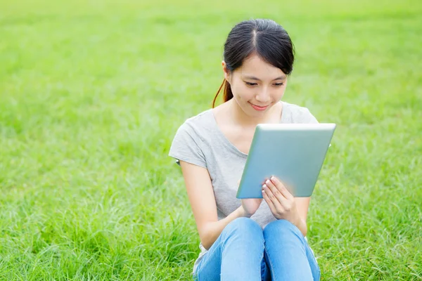 Žena sedí na trávě s tabletovým počítačem — Stock fotografie