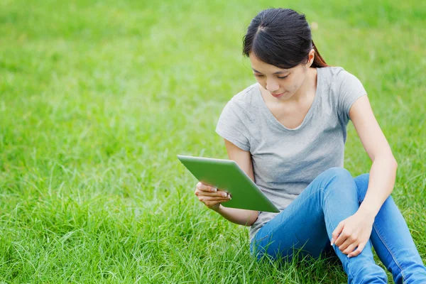 Femme assise sur l'herbe avec tablette — Photo