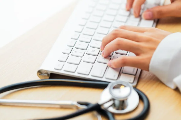 Doctor typing keyboard with stethoscope — Stockfoto