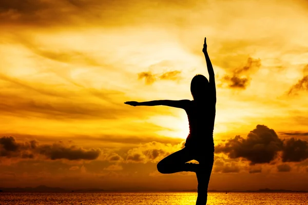 Femme faisant du yoga pendant le coucher du soleil — Photo