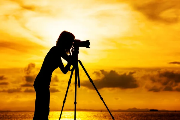 Silhouette kvinnlig fotograf vid solnedgången — Stockfoto