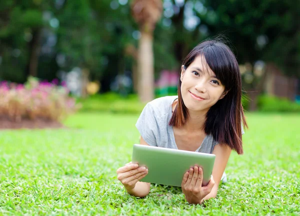 Kvinna liggande på gräs med tablet PC — Stockfoto