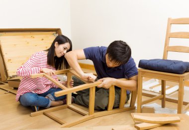 Asian couple assembling new chair clipart