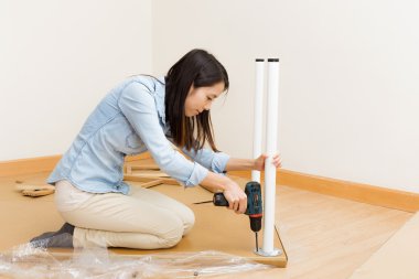 Asian woman using strew driver for assembling furniture clipart