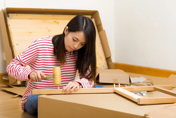 Asian woman using hammer for furniture assembling — Stock Photo, Image