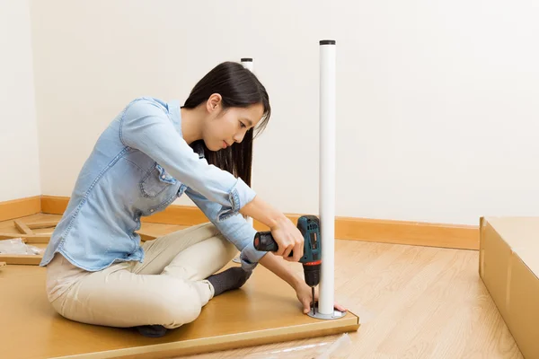 Asian woman using strew driver for assembling furniture — Stock Photo, Image