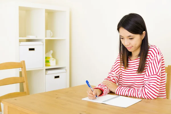 Asiatisk kvinna skriver på anteckningsboken — Stockfoto