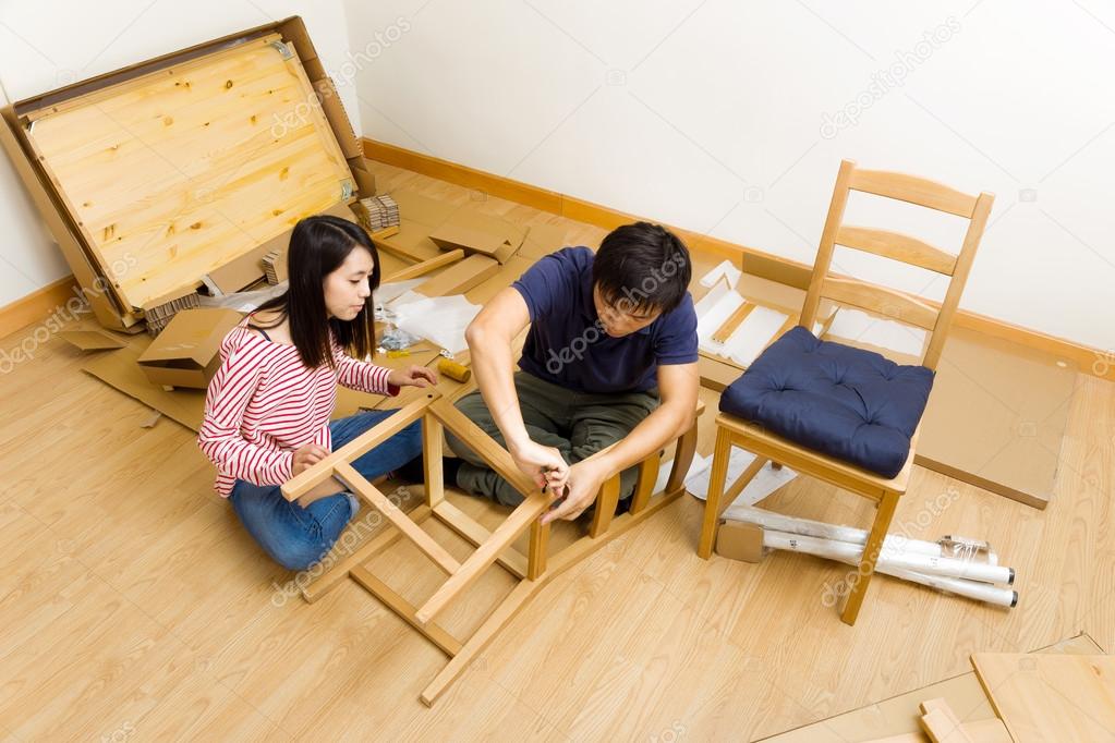 Asian couple assembling furniture for new house