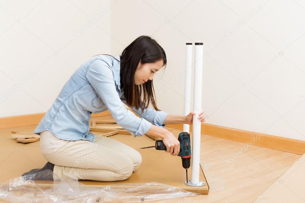 Asian woman using strew driver for assembling furniture