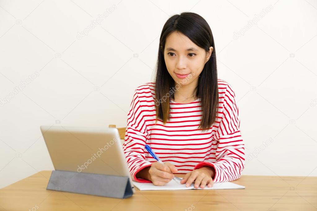 Asian woman writing notes through digital tablet