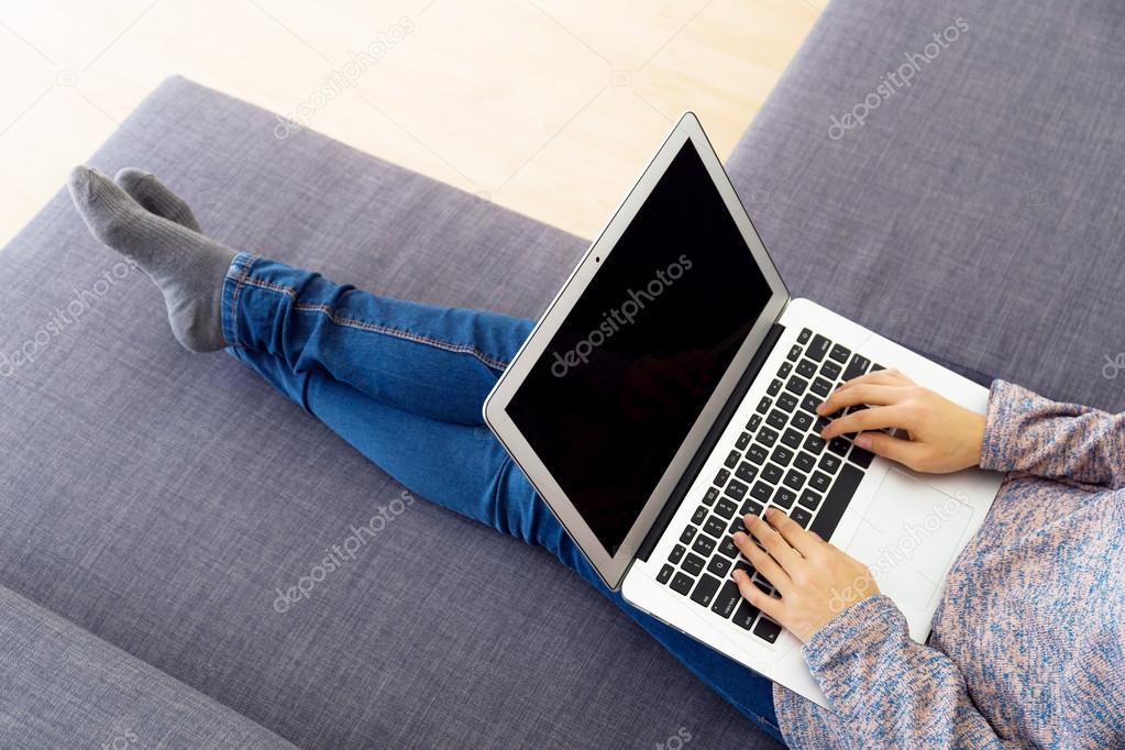 Asian woman using laptop on sofa